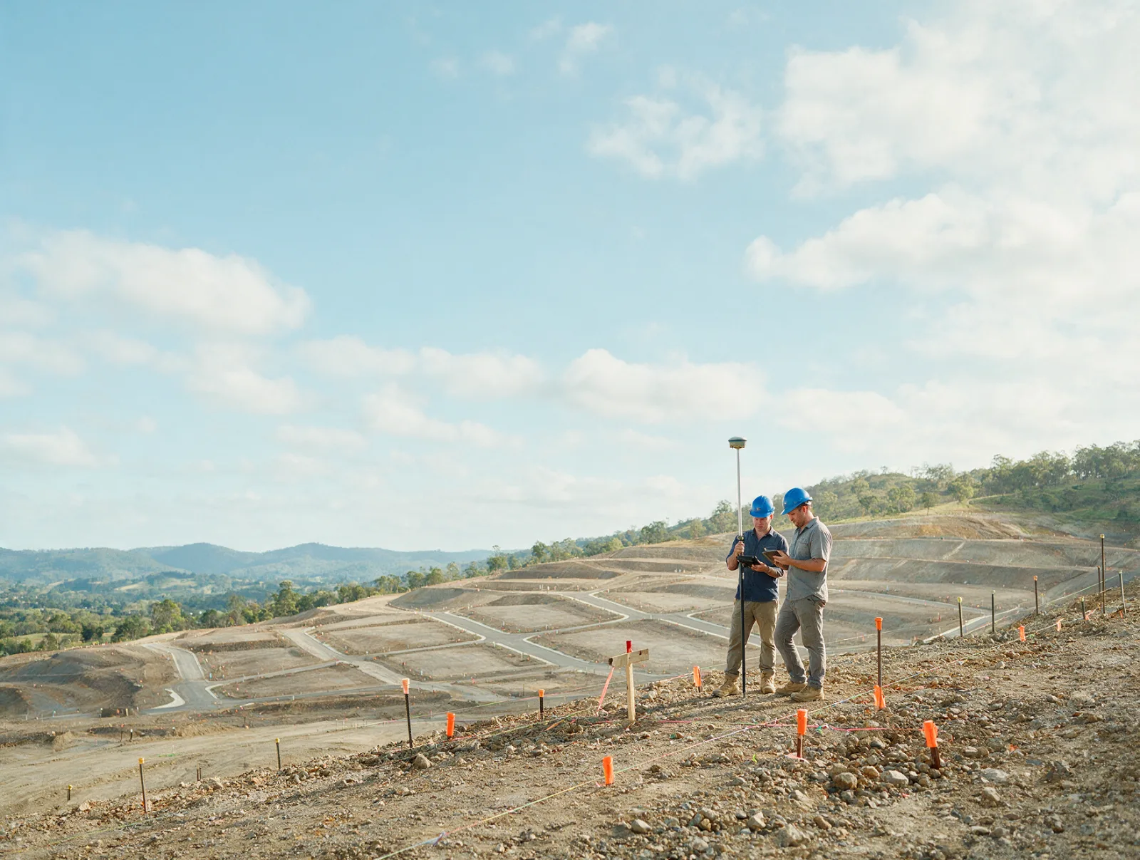 Dois topógrafos com GNSS e tablet em loteamento em terraplenagem numa encosta